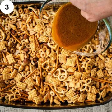 Brown sauce being poured over a mixture of cereal, nuts and pretzels.