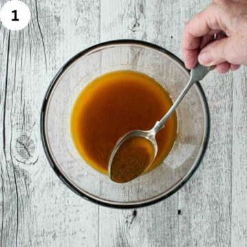 Brown sauce in a glass bowl being scooped up with a spoon.