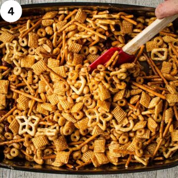 Mixture of cereal, nuts and pretzels being stirred with red spatula.