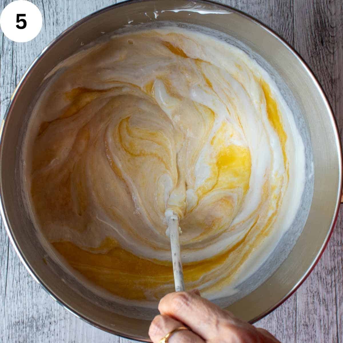 Stirring white and orange creamy mixture together.