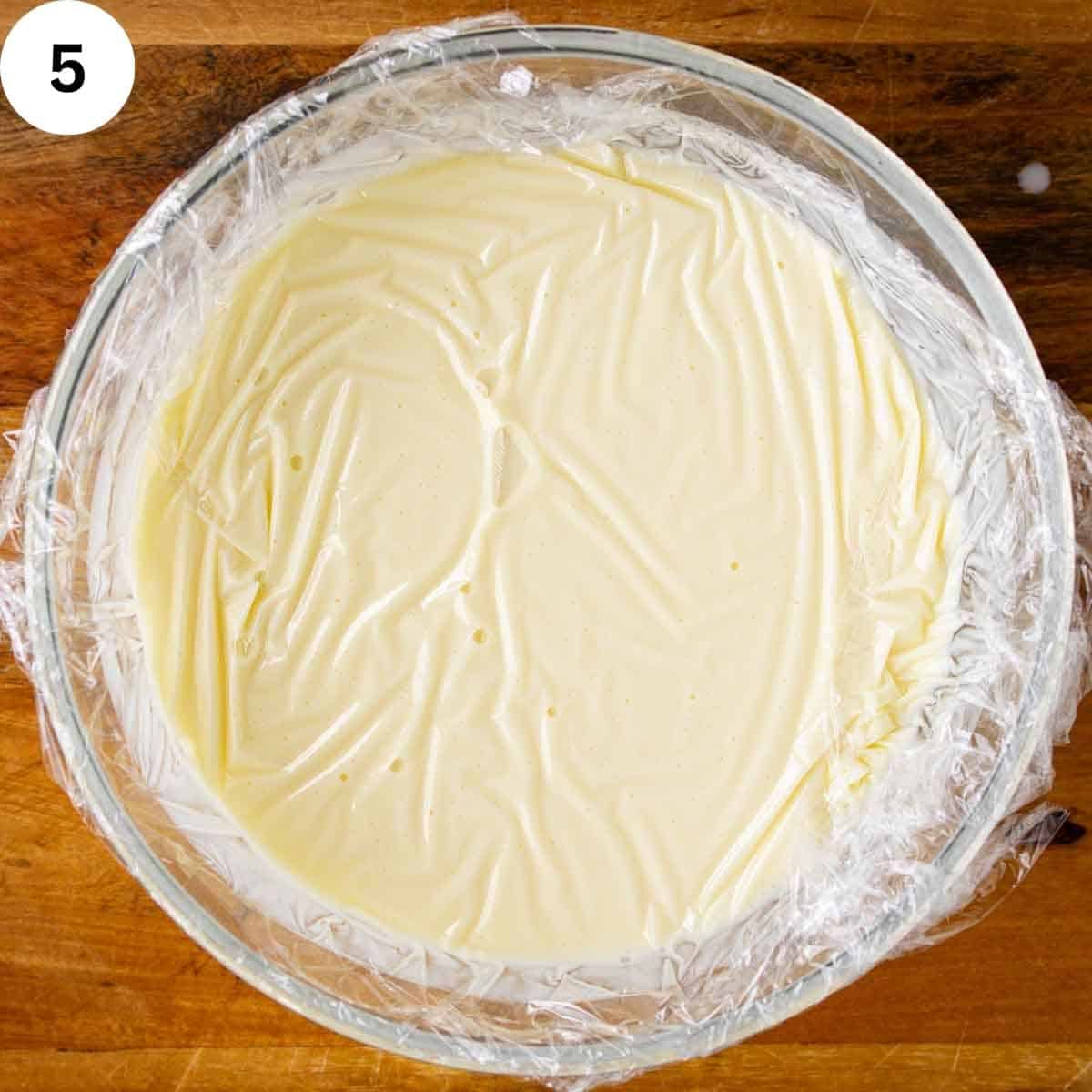 Creamy liquid covered with plastic wrap.