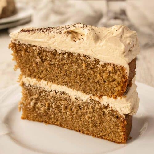 Close up of a wedge of two layer cake filled and topped with buttercream.