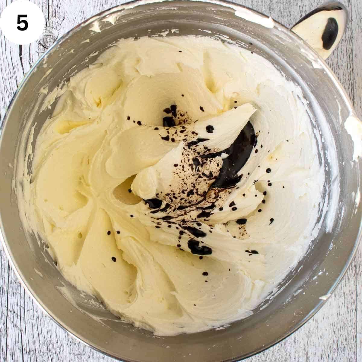 Small amount of dark liquid on creamy butter mixture in a bowl.