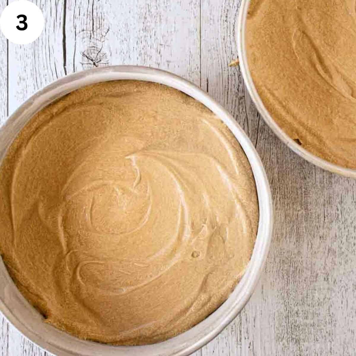 Cake batter divided into two round cake pans.