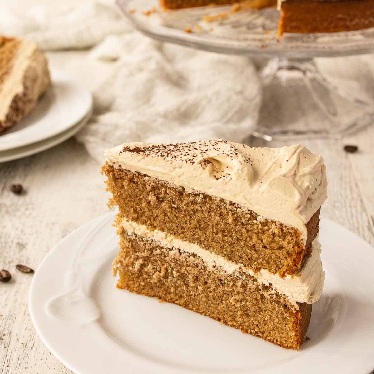Cappuccino Cake with a slice on a plate and remaining cake in background.