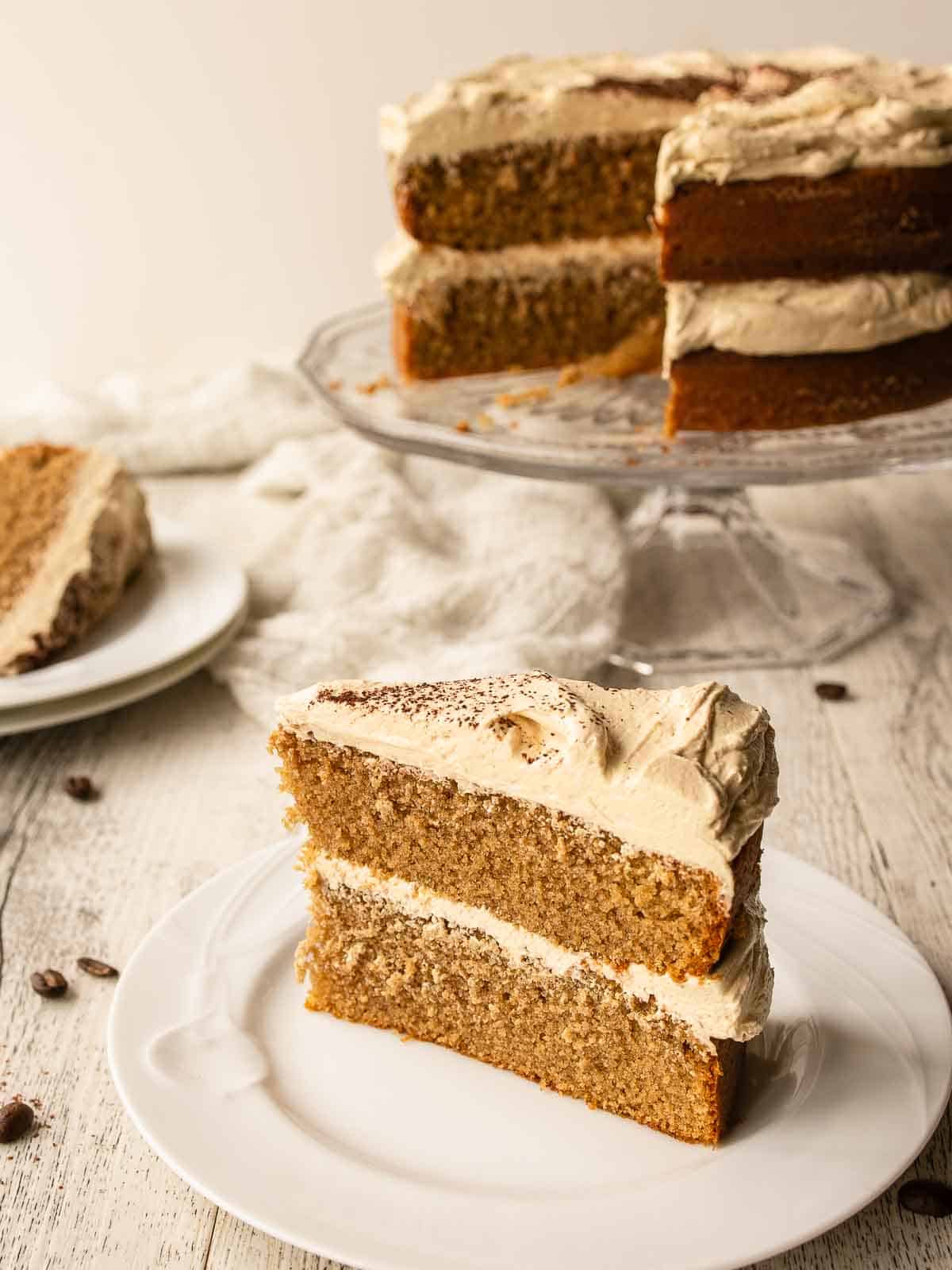 Cappuccino Cake with a slice on a plate and remaining cake in background.