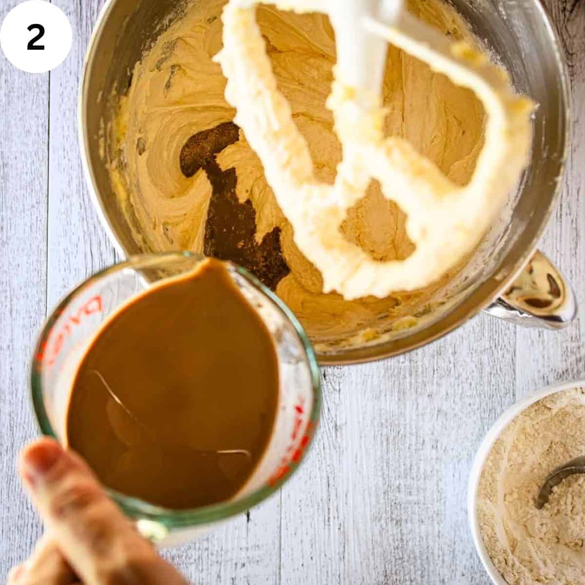 Pouring brown liquid into creamy mixture in a stand mixer bowl.