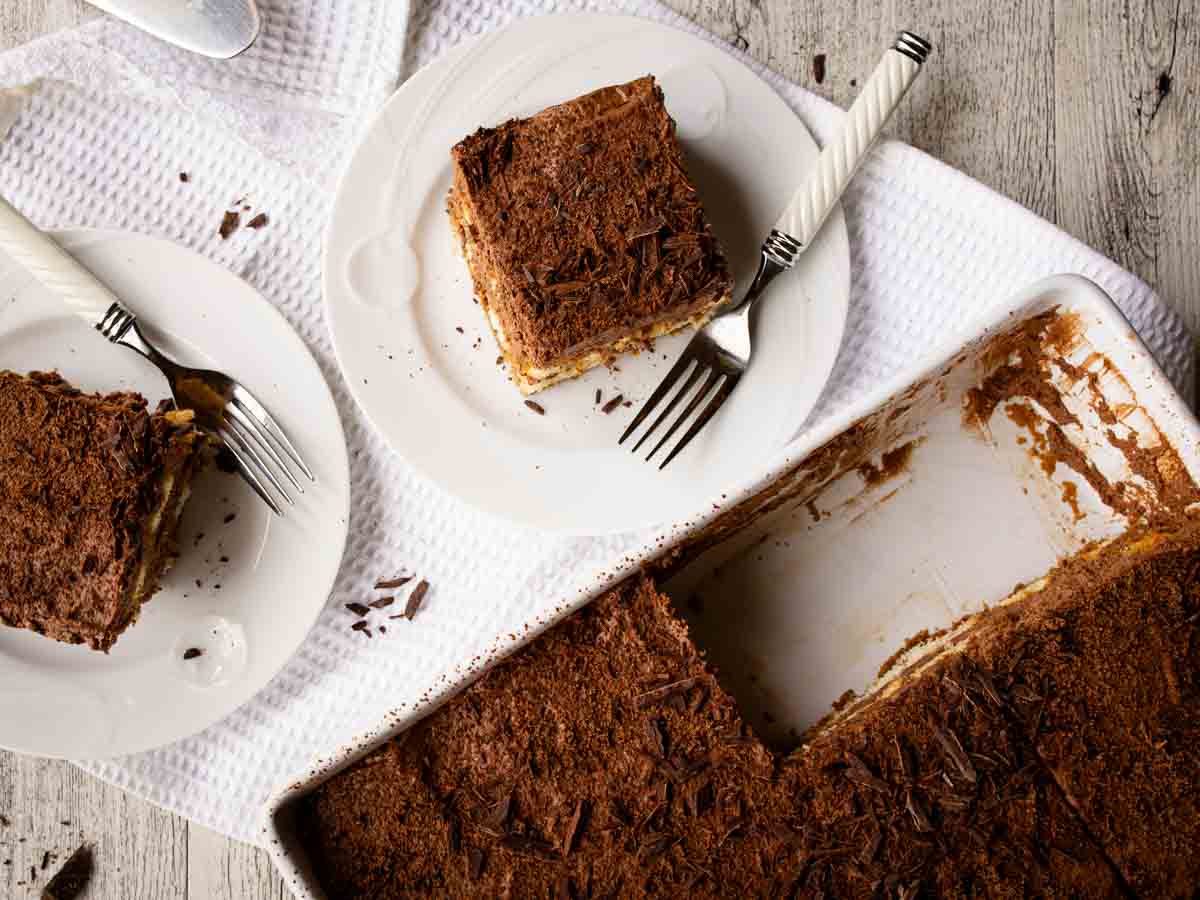 Overhead view of chocolate dessert cut into squares on white plates.