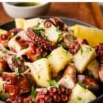 Octopus salad in a bowl on a wooden board.