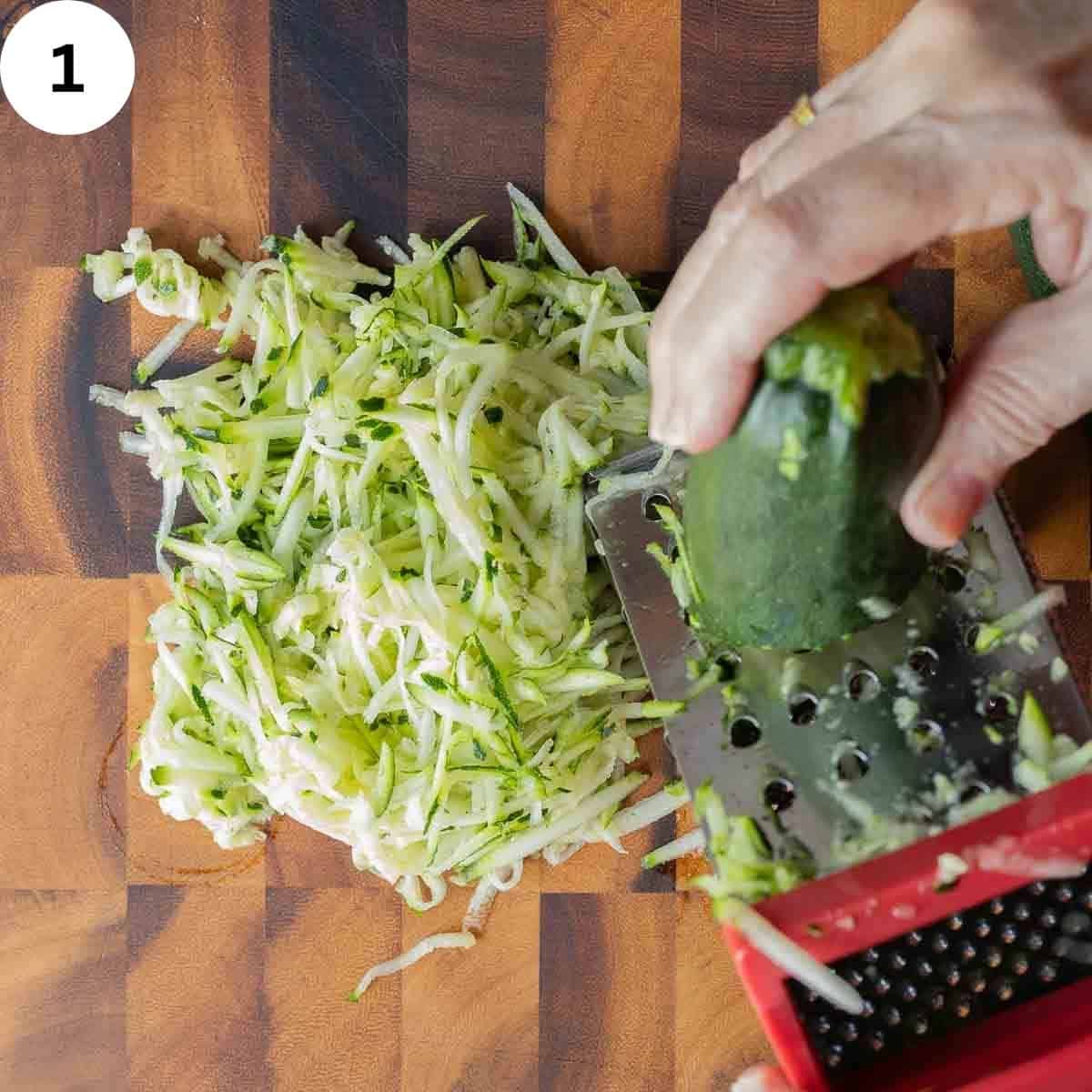 Zucchini being shredded on a coarse grater.