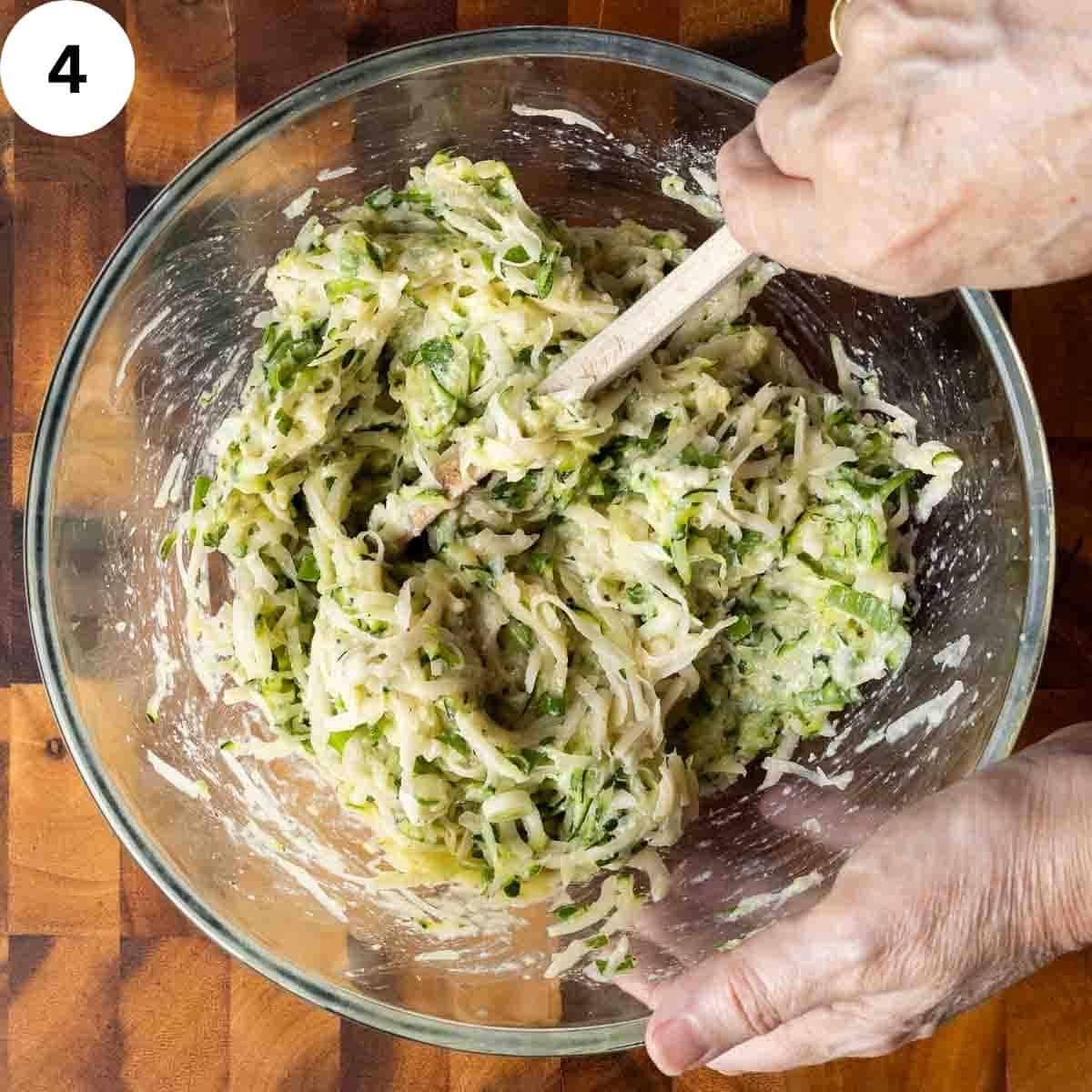 Thick batter with flecks of green being stirred in a glass bowl.