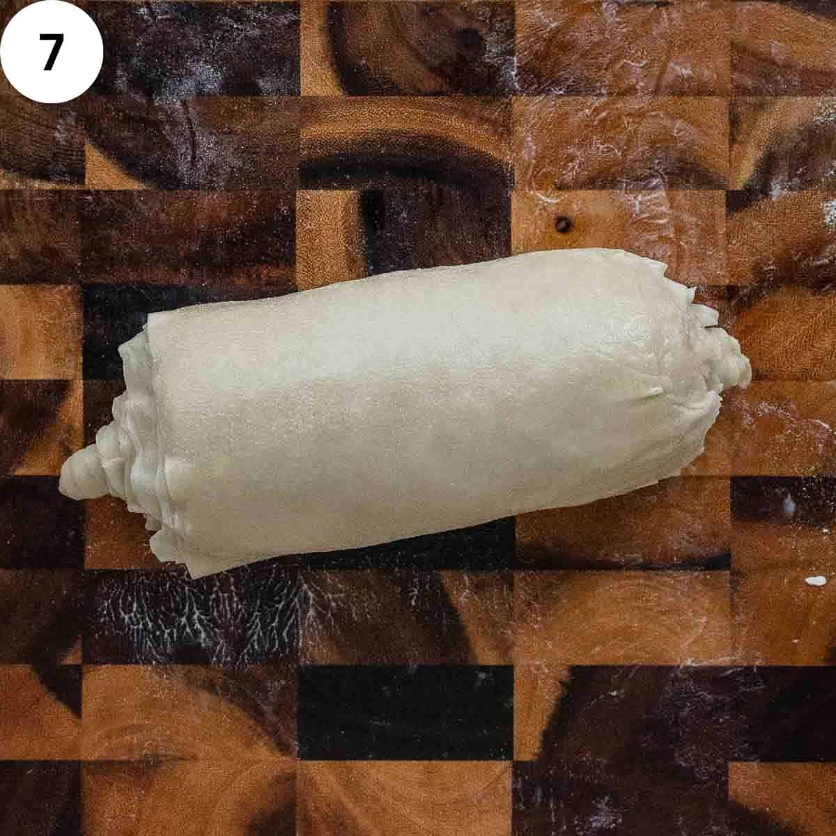A dough log on a wooden board.
