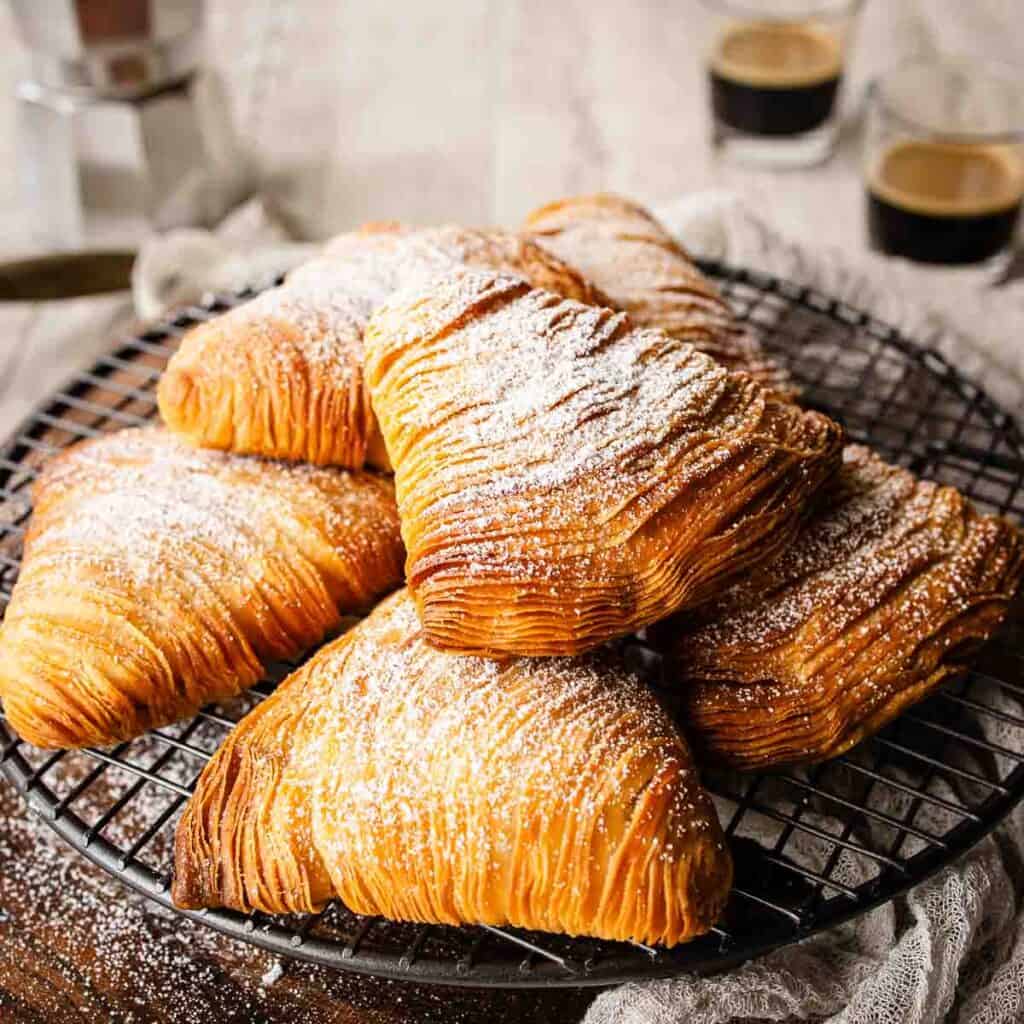 Flaky Sfogliatelle piled onto a round wire rack.