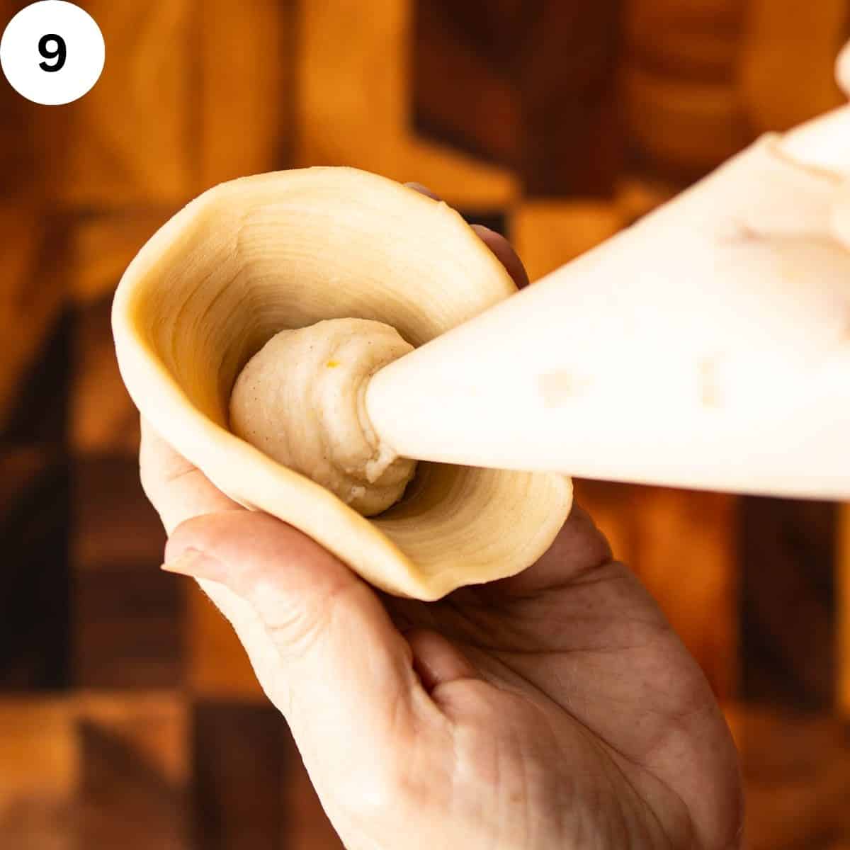 Creamy filling being piped into a pastry cone.