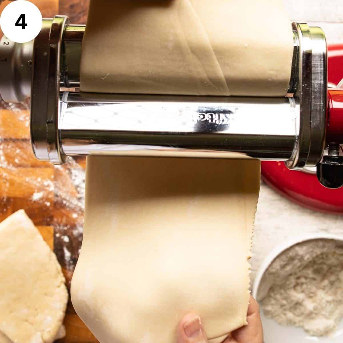 Dough being fed through the rollers of a pasta machine.