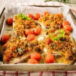 Baked Swordfish with a gratin topping surrounded by baked cherry tomatoes.