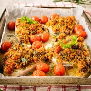 Baked Swordfish with a gratin topping surrounded by baked cherry tomatoes.