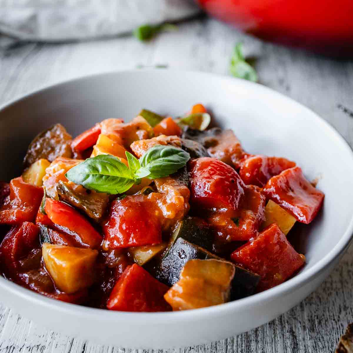 Ciambotta in a bowl with more in the background in a round pan.