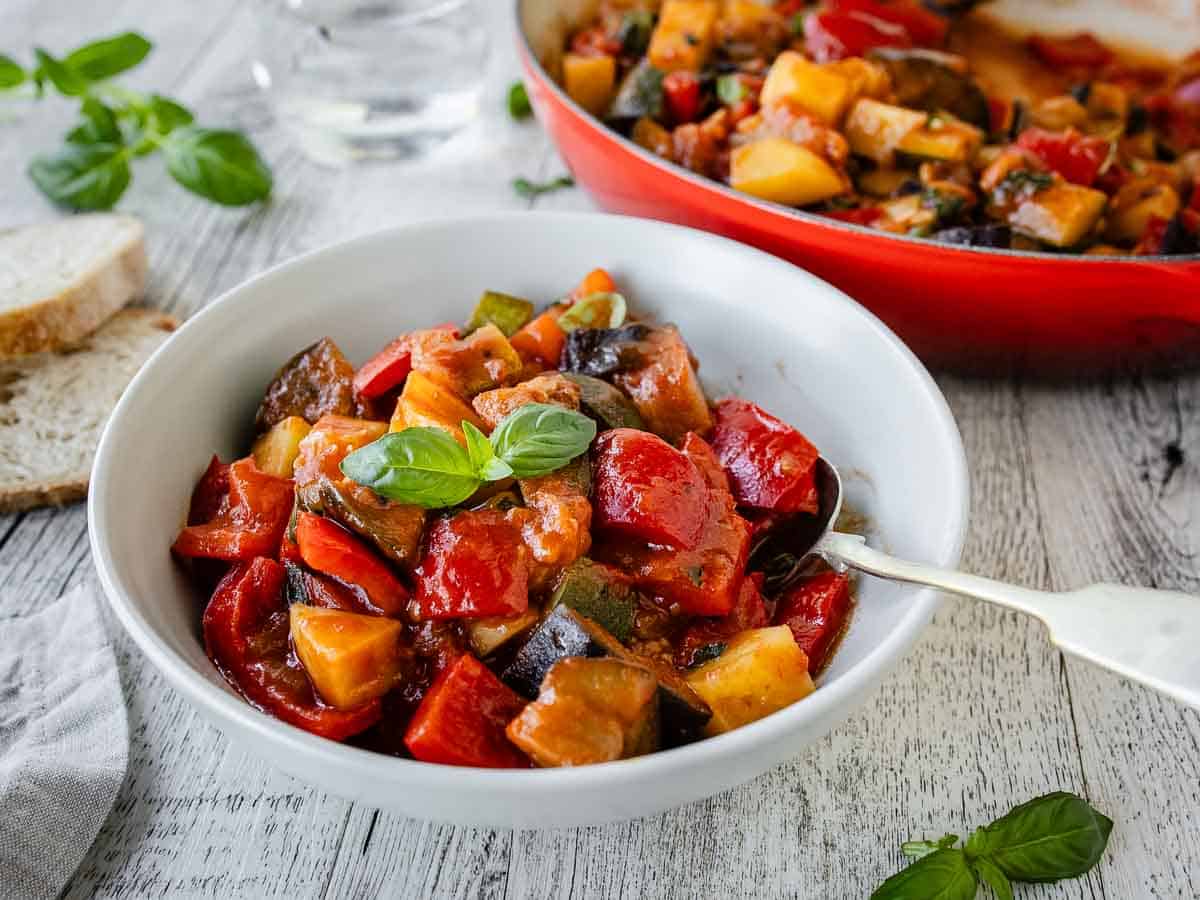 Italian Ratatouille in a bowl with more in the background in a round pan.