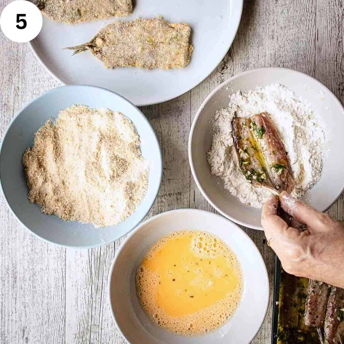 Breading butterflied sardines using flour, egg and bread crumbs.