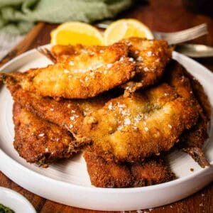 Fried sardines piled up on a round plate.
