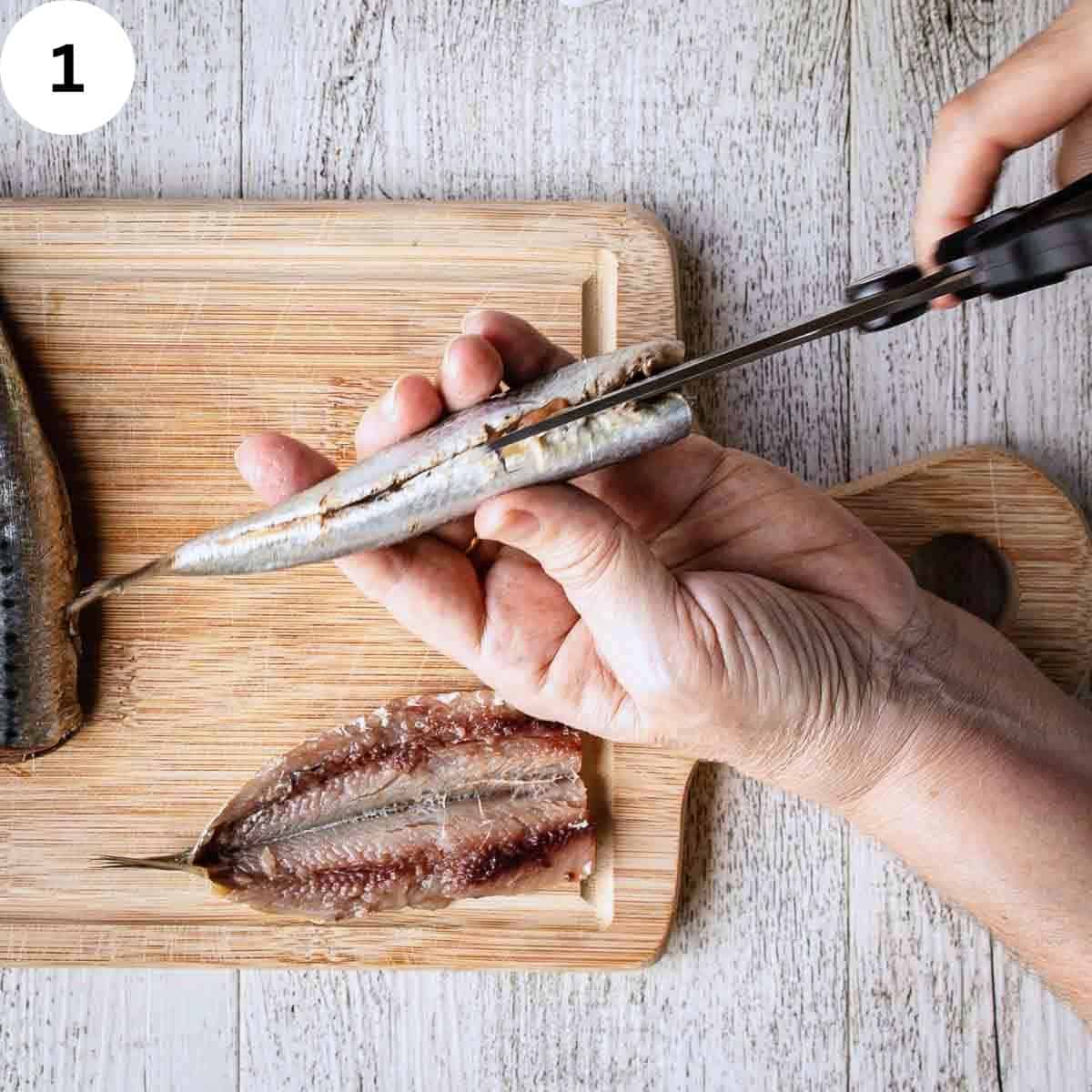 Cutting the belly of sardines with sissors.