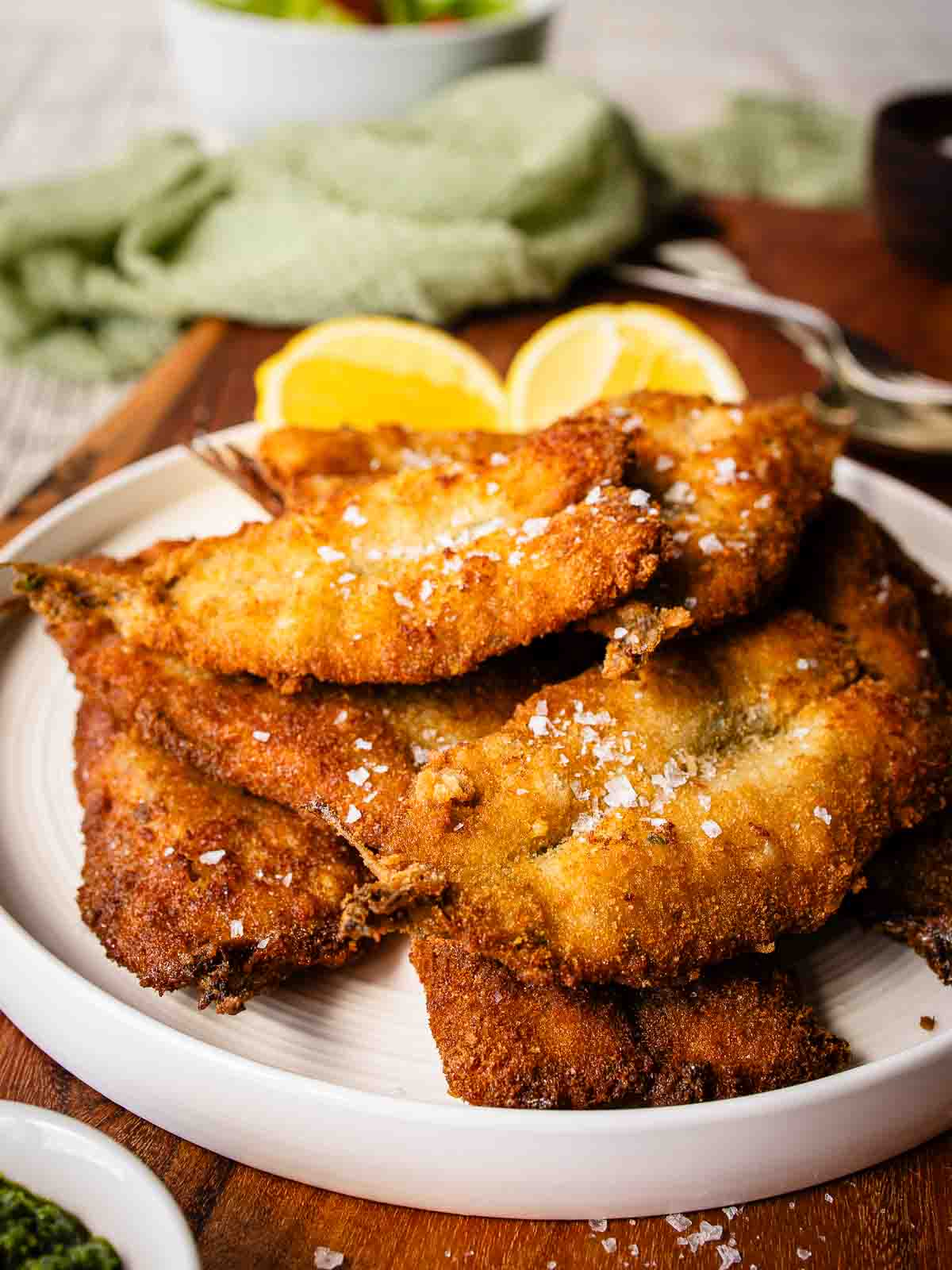 Fried sardines piled up on a round plate.