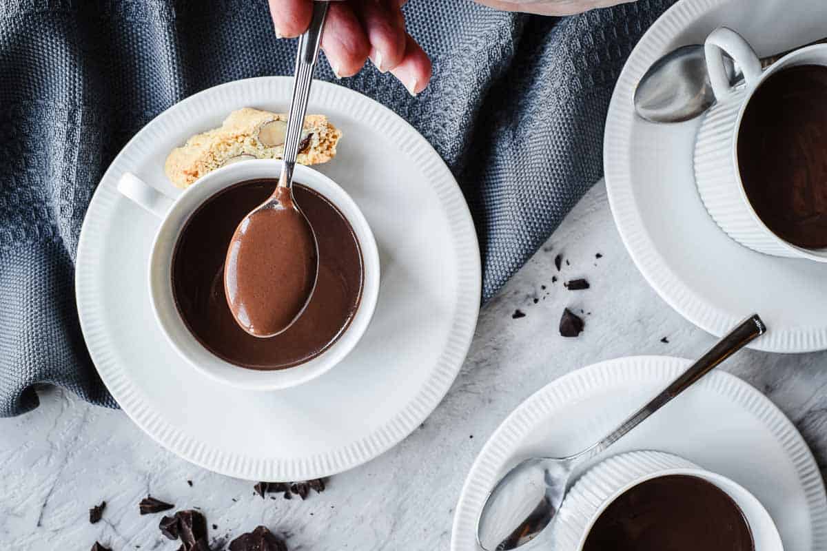 This Italian Hot Chocolate recipe makes it easy to create an authentic and decadent drink. #italianhotchocolate #italianrecipe #hotchocolate #easy #thickhotchocolate #authenticitalian A spoonful of thick chocolate mixture held above a cupful of the mixture.