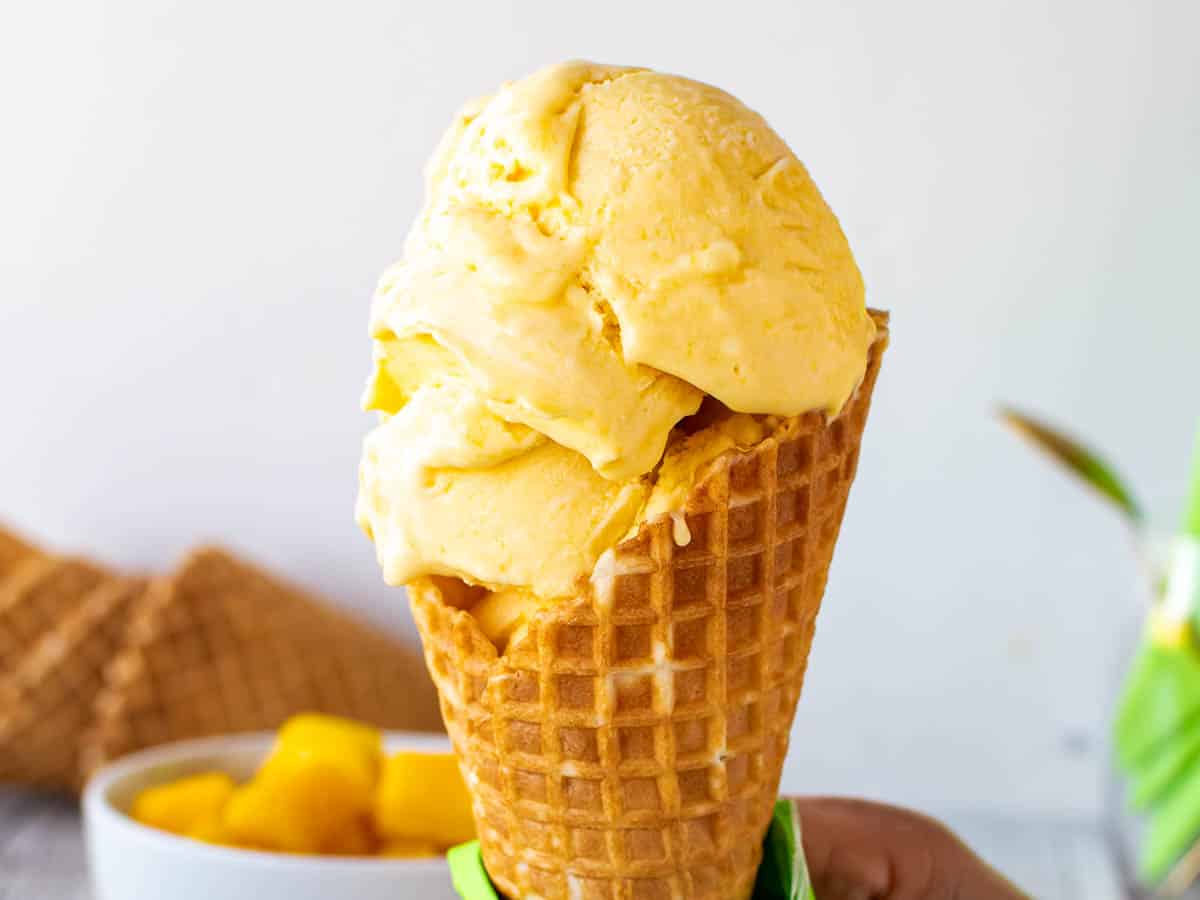 Close up of scoops of yellow ice cream in a cone.