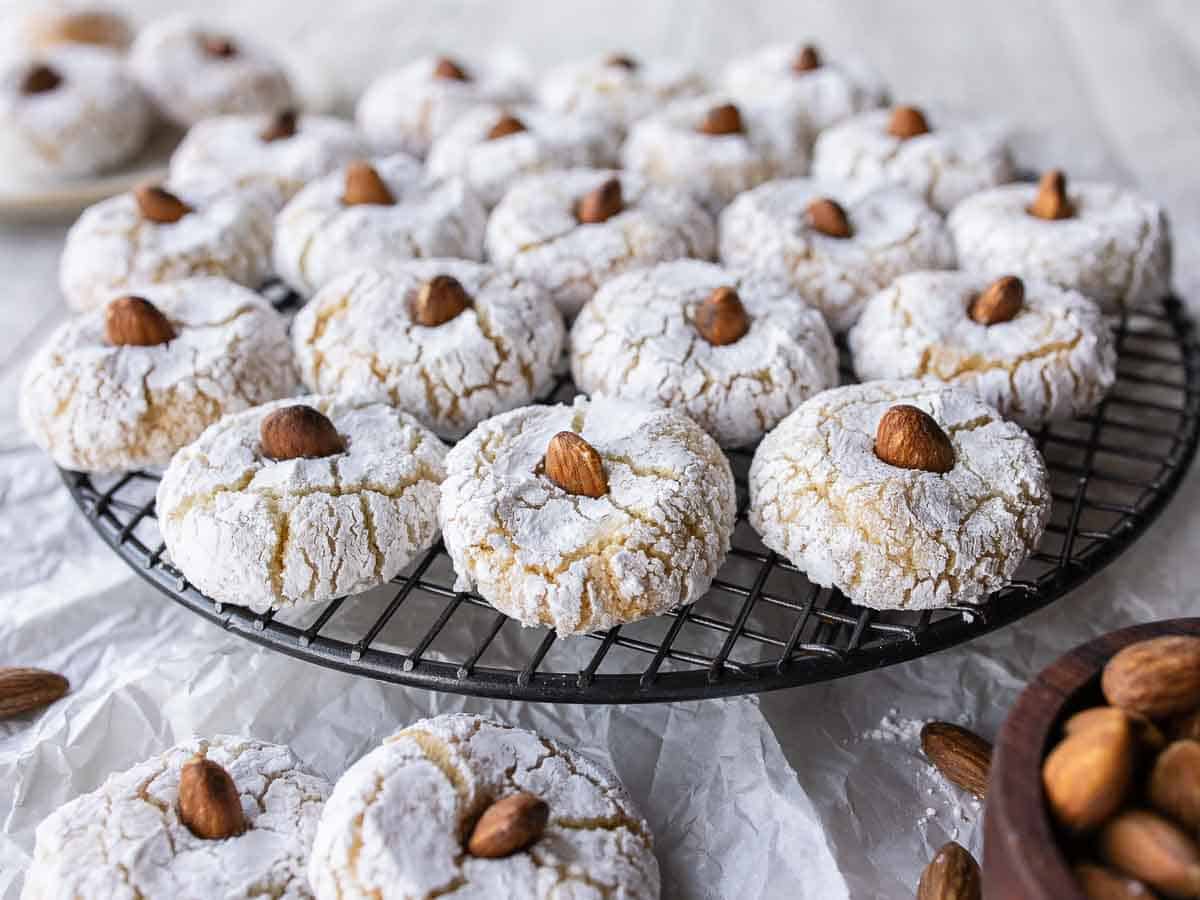 Close up of cookies with almond on top on a round wire rack.