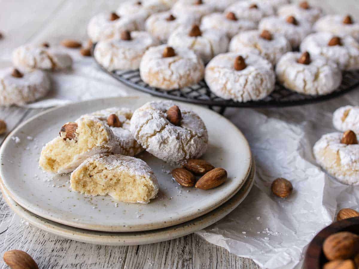 Italian almond cookies on a plate, broken in half, with more cookies in the background.