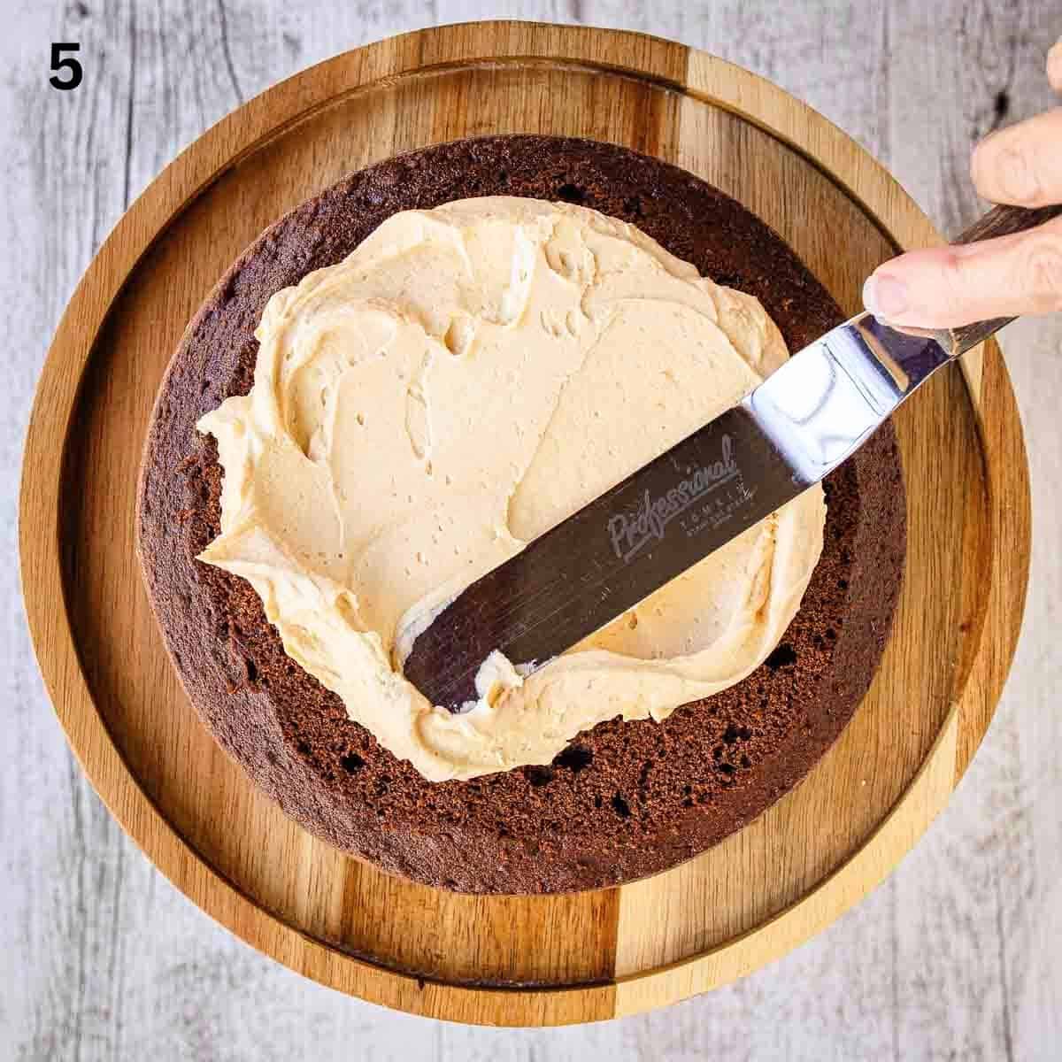 Spreading buttercream onto a chocolate cake.