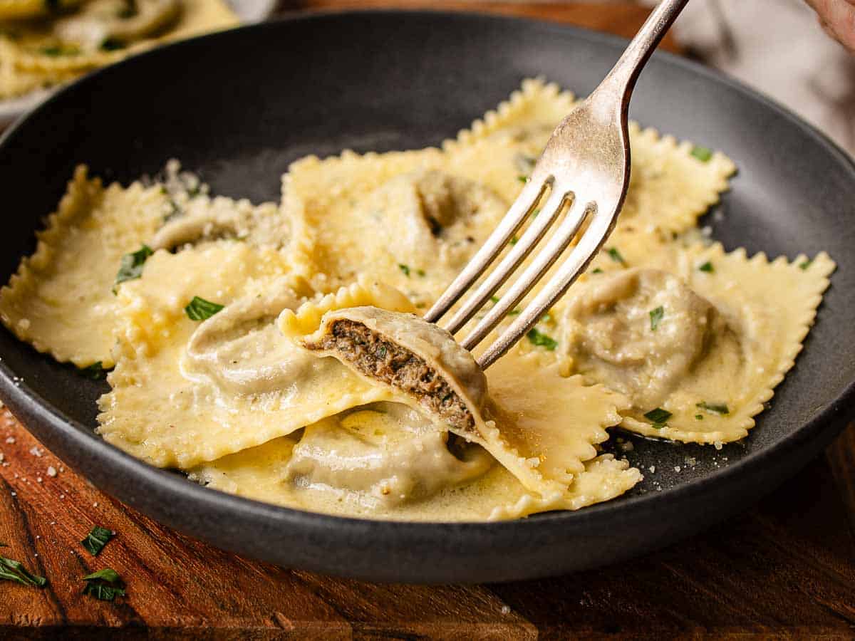 Ravioli filled with mushrooms, cut in half and held on a fork.