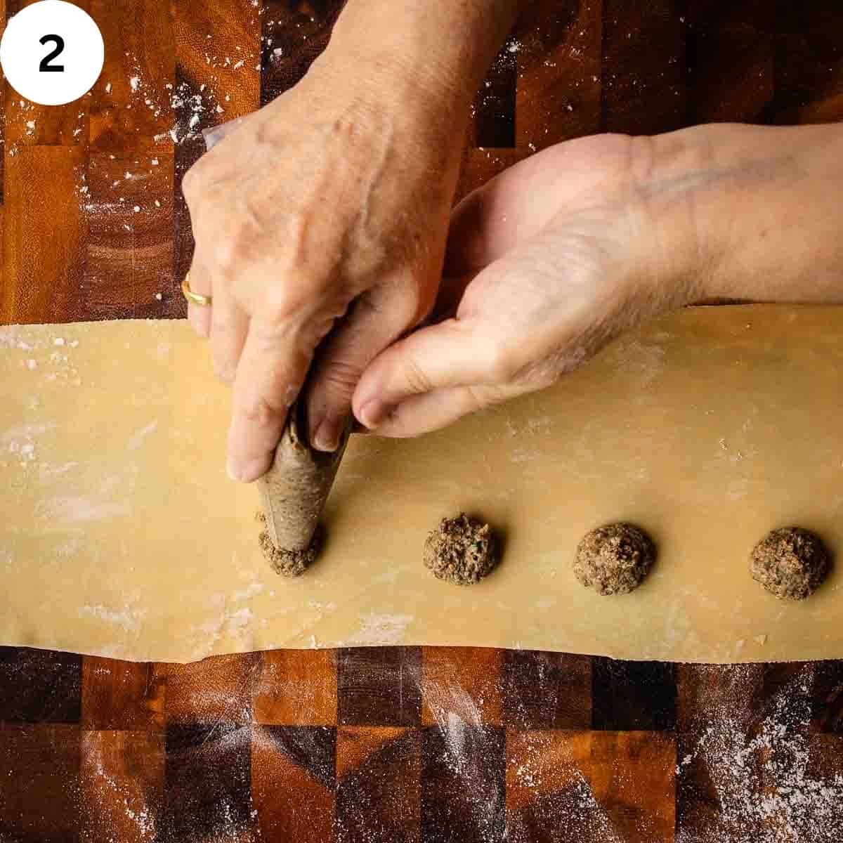 Mushroom filling being piped onto a thinned sheet of pasta dough.