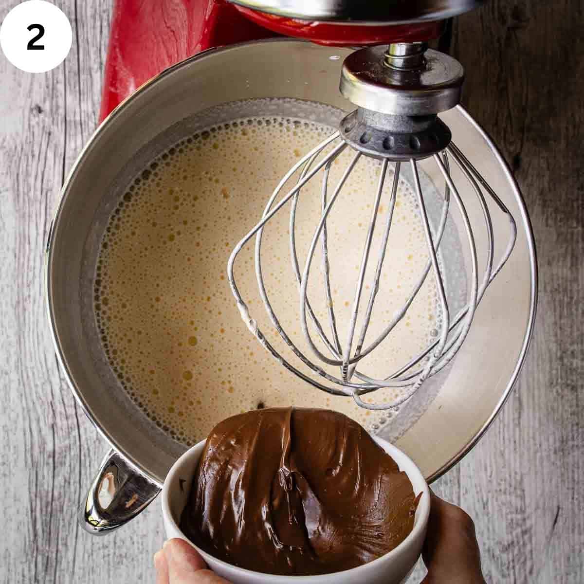 Adding chocolate hazelnut spread to bowl of stand mixer filled with thick creamy mixture.