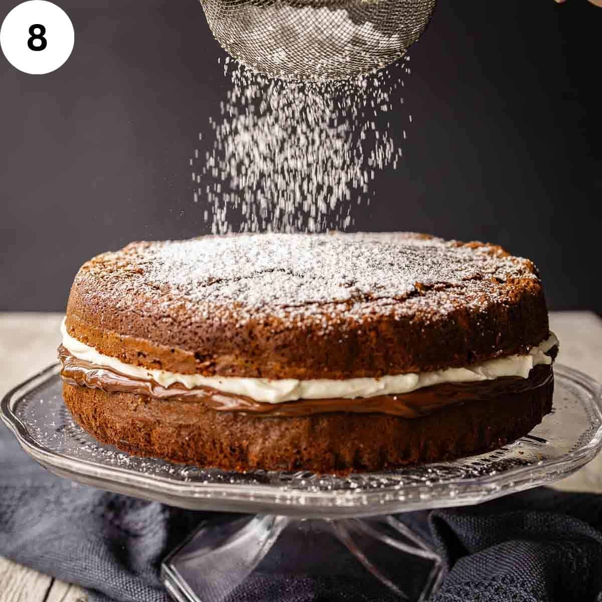 Powdered sugar being sprinkled on top of a two layered chocolate cake.