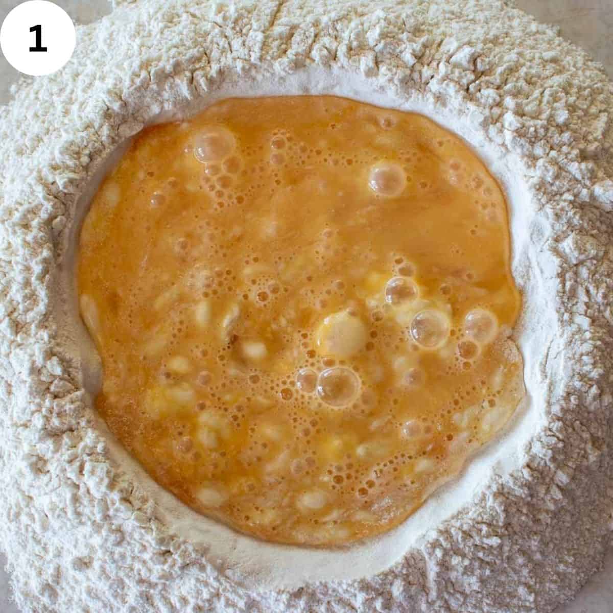 Beaten eggs in a well of flour.