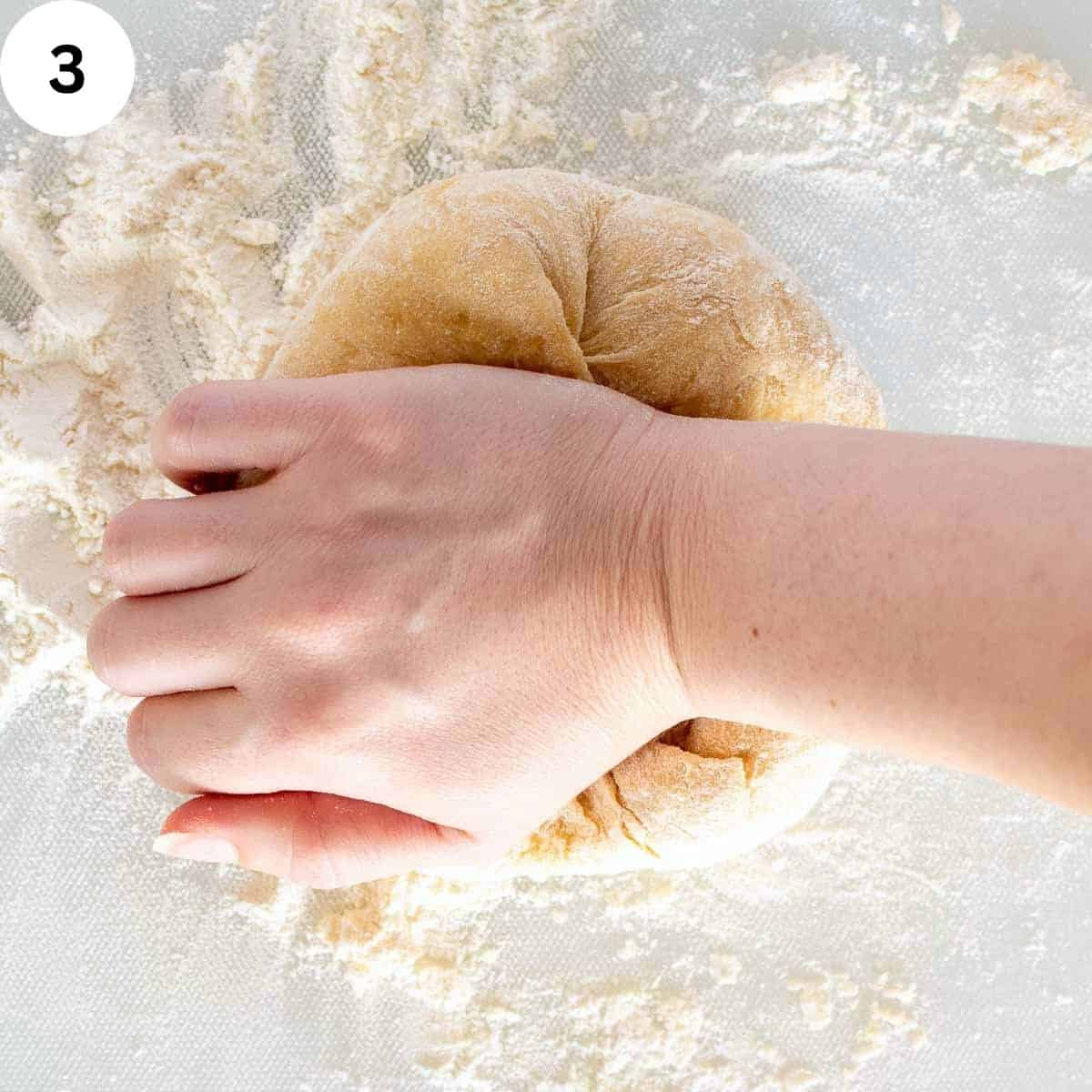 A hand kneading pasta dough.