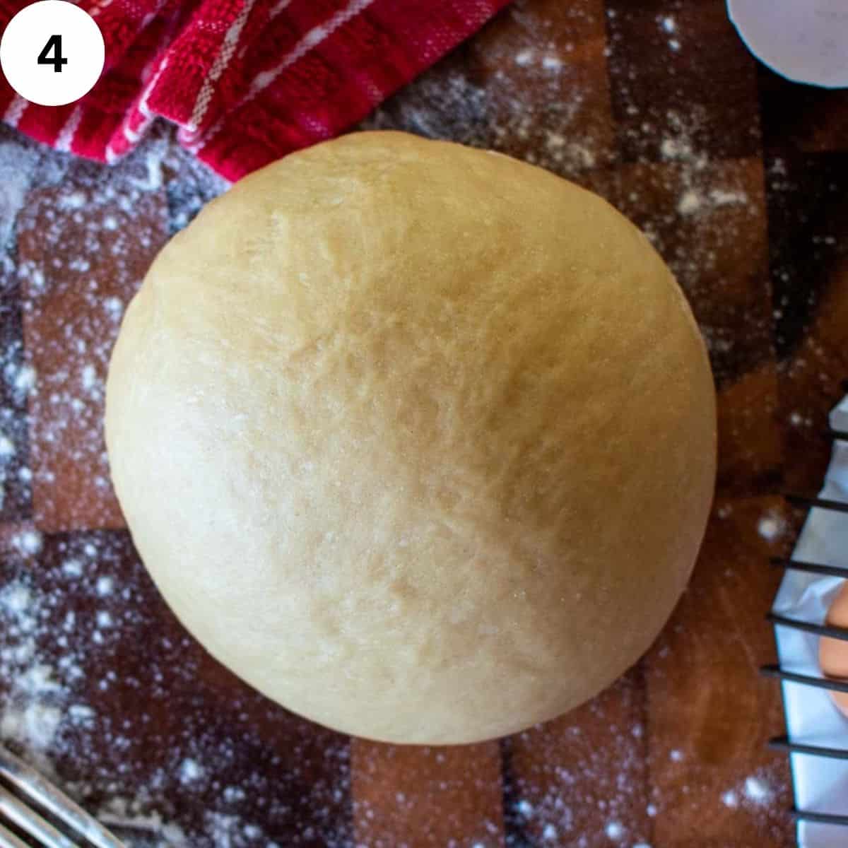 A ball of pasta dough on a wooden board.