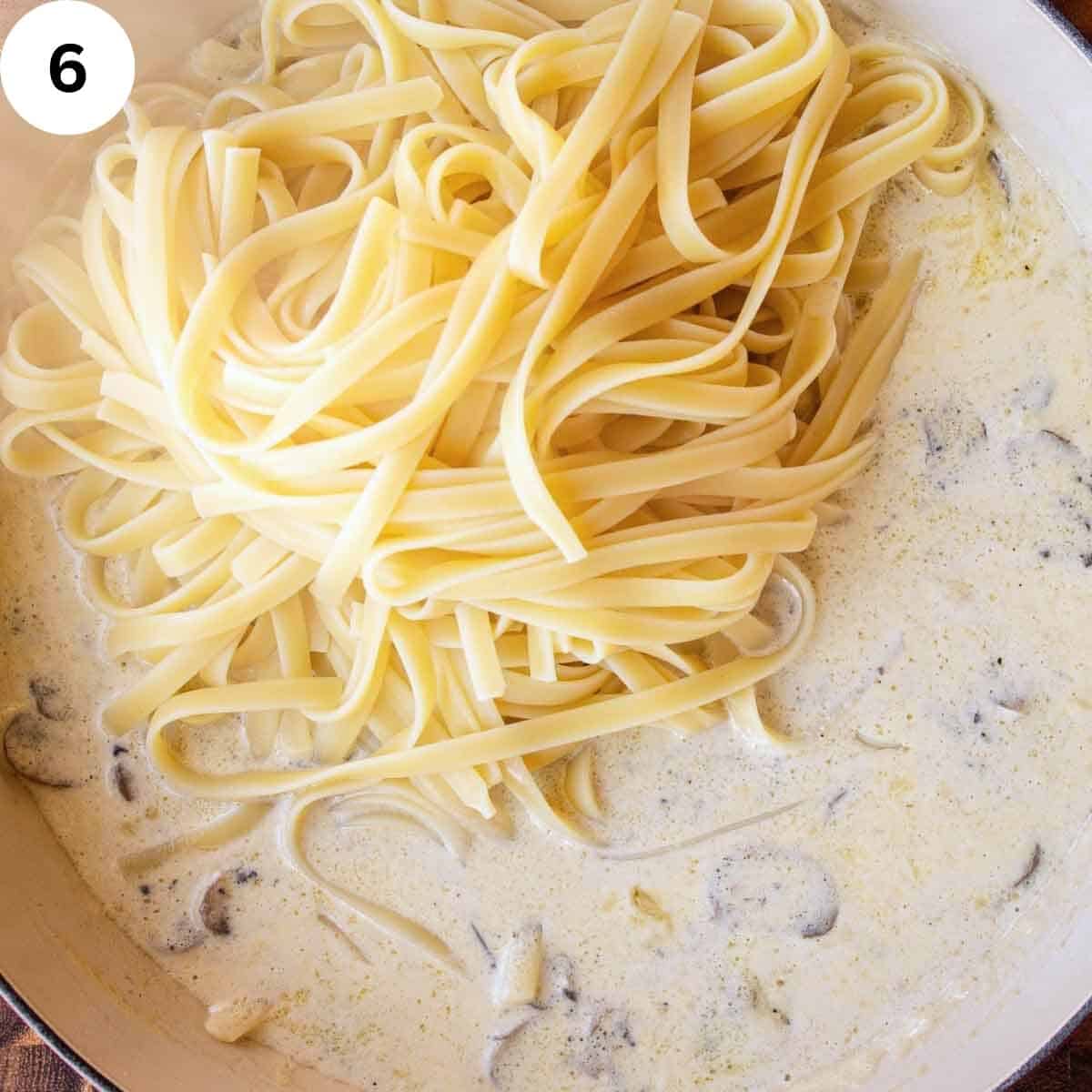 Cooked fettuccini pasta being added to a creamy sauce.
