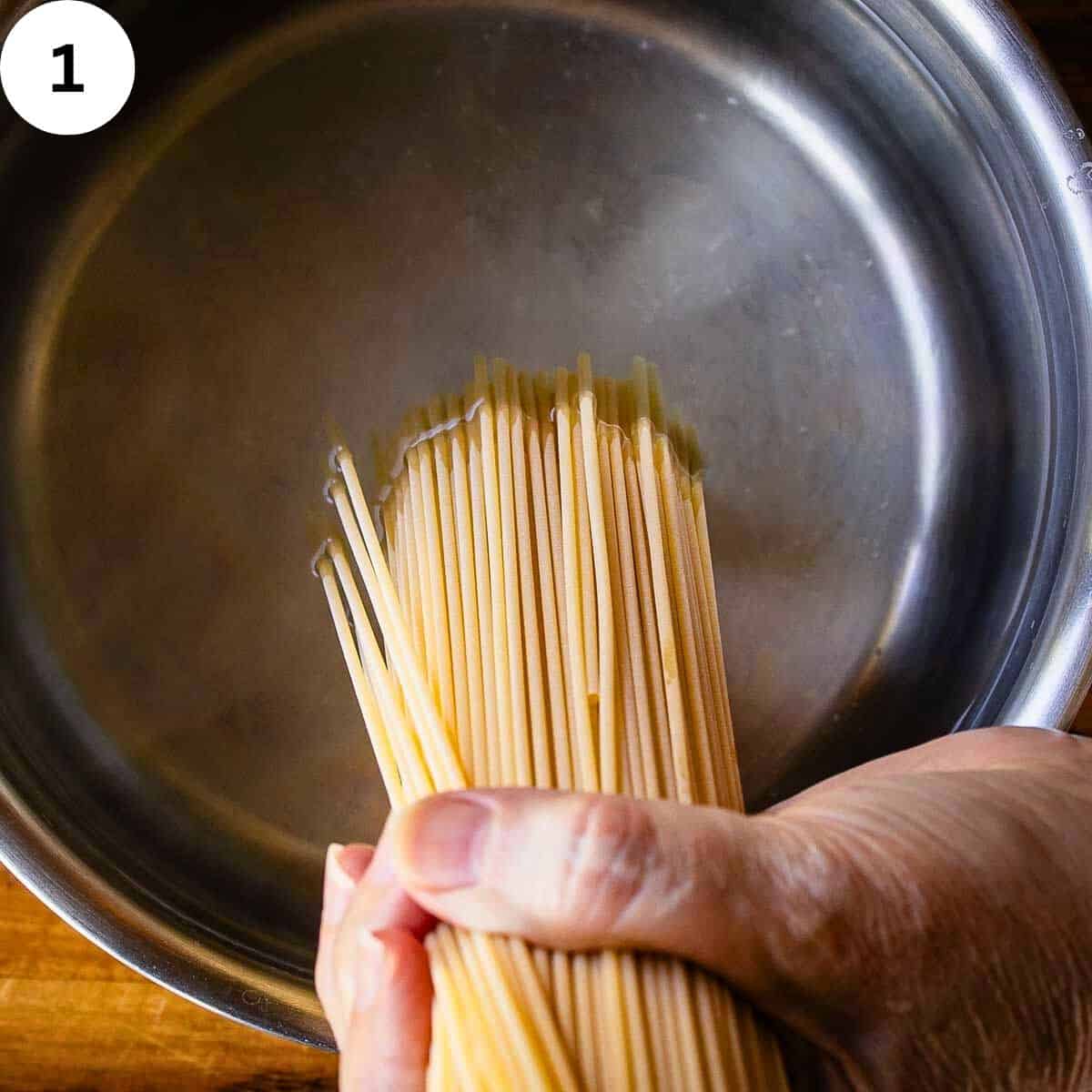 Spaghetti being dropped into pot of water.