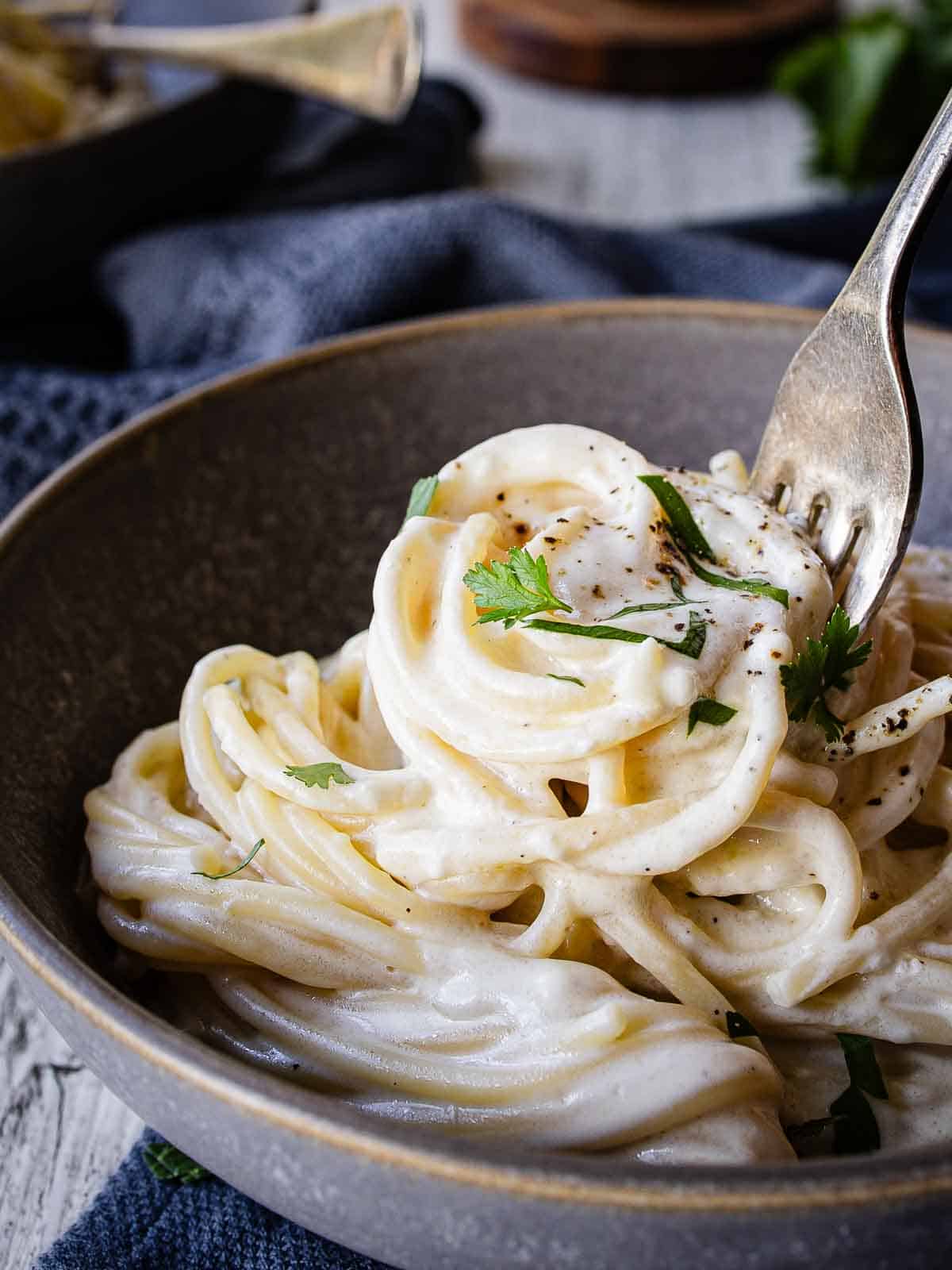 Cream cheese pasta in a bowl being twirled onto a fork.