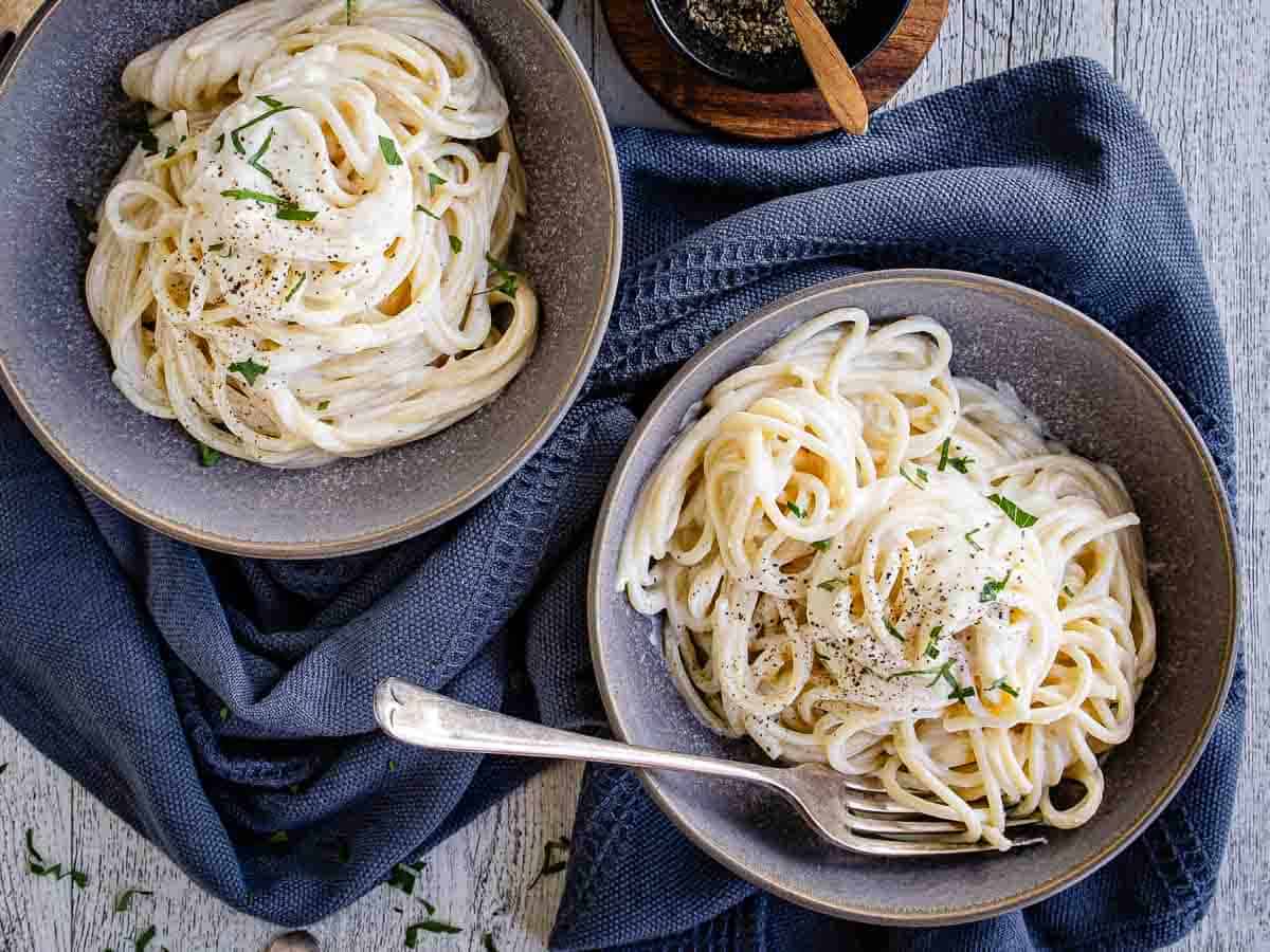 Overhead view of pasta with cream cheese sauce in two bowls.
