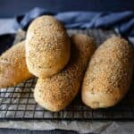 Italian cheese and herb bread loaves piled up on a wire rack.