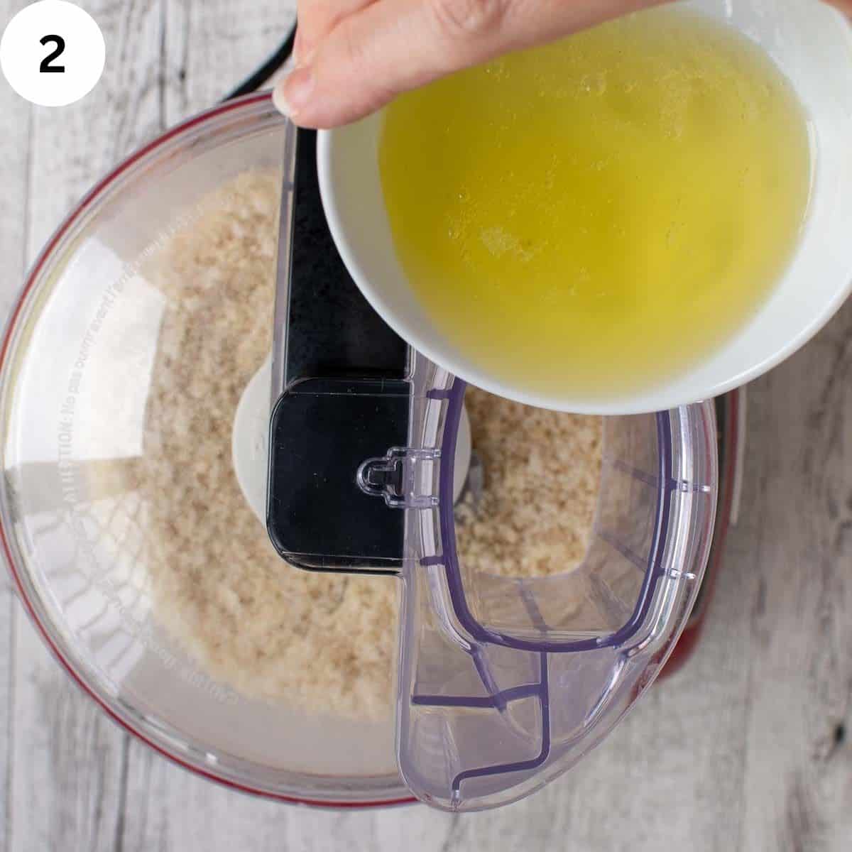Egg white being poured into the spout of a food processor.
