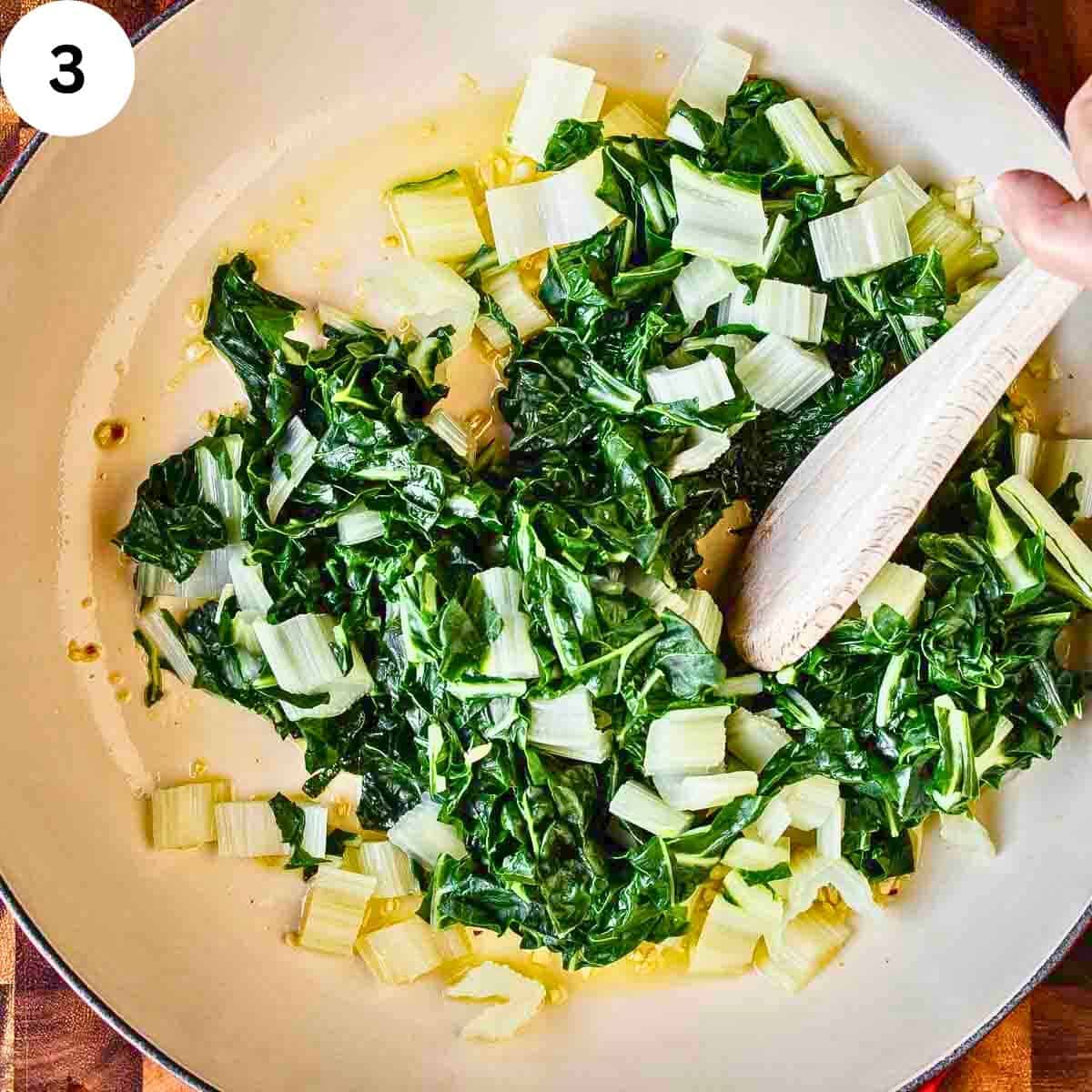 Chopped and cooked Swiss chard in pan with oil, garlic and red pepper flakes.