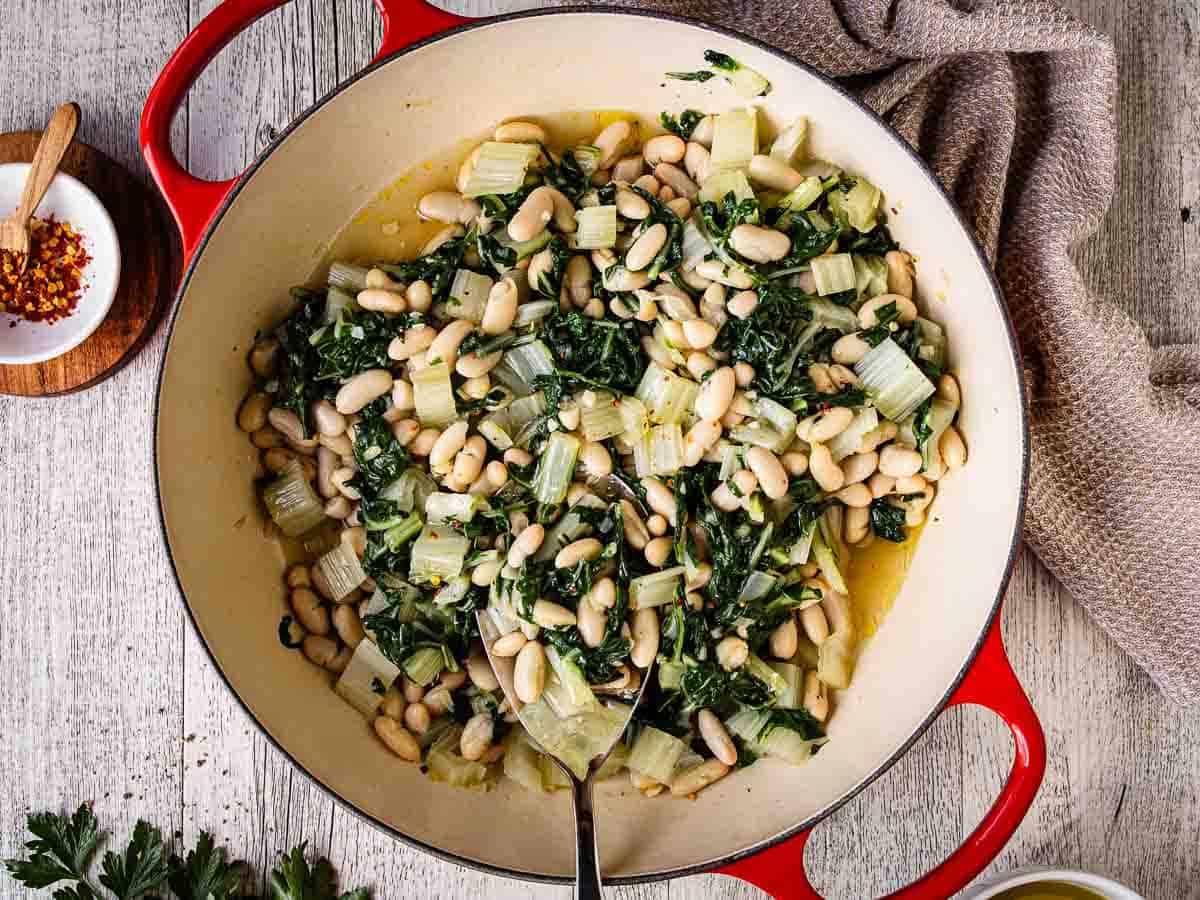 Overhead view of greens and beans in a pan with two handles.