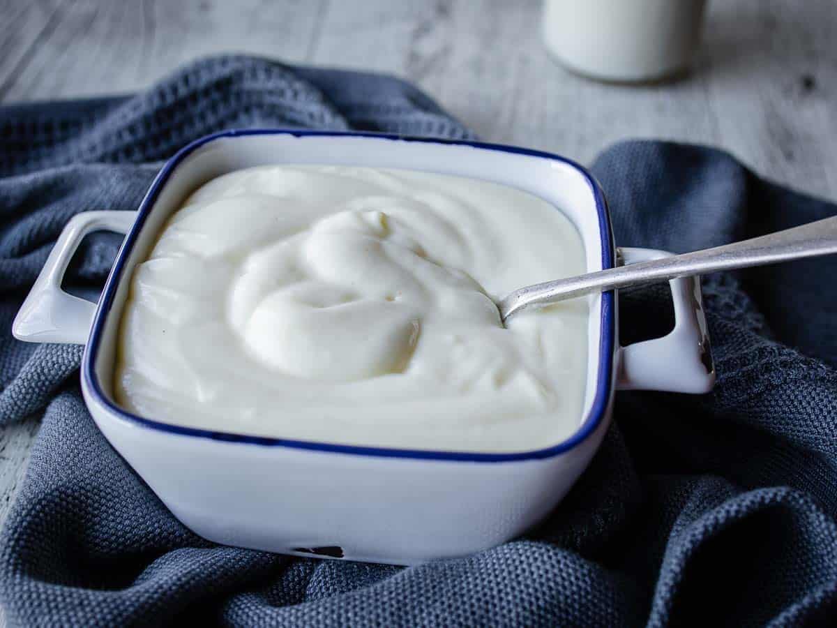 Thick white sauce in a square bowl in a spoon in the sauce.