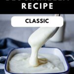 Besciamella sauce pouring off a spoon and into a bowl.