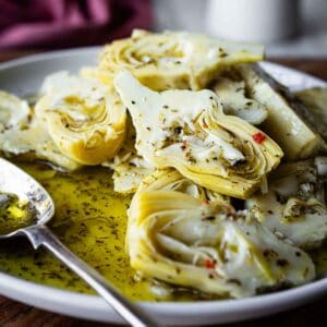 Close up of marinated artichokes plied onto a plate.